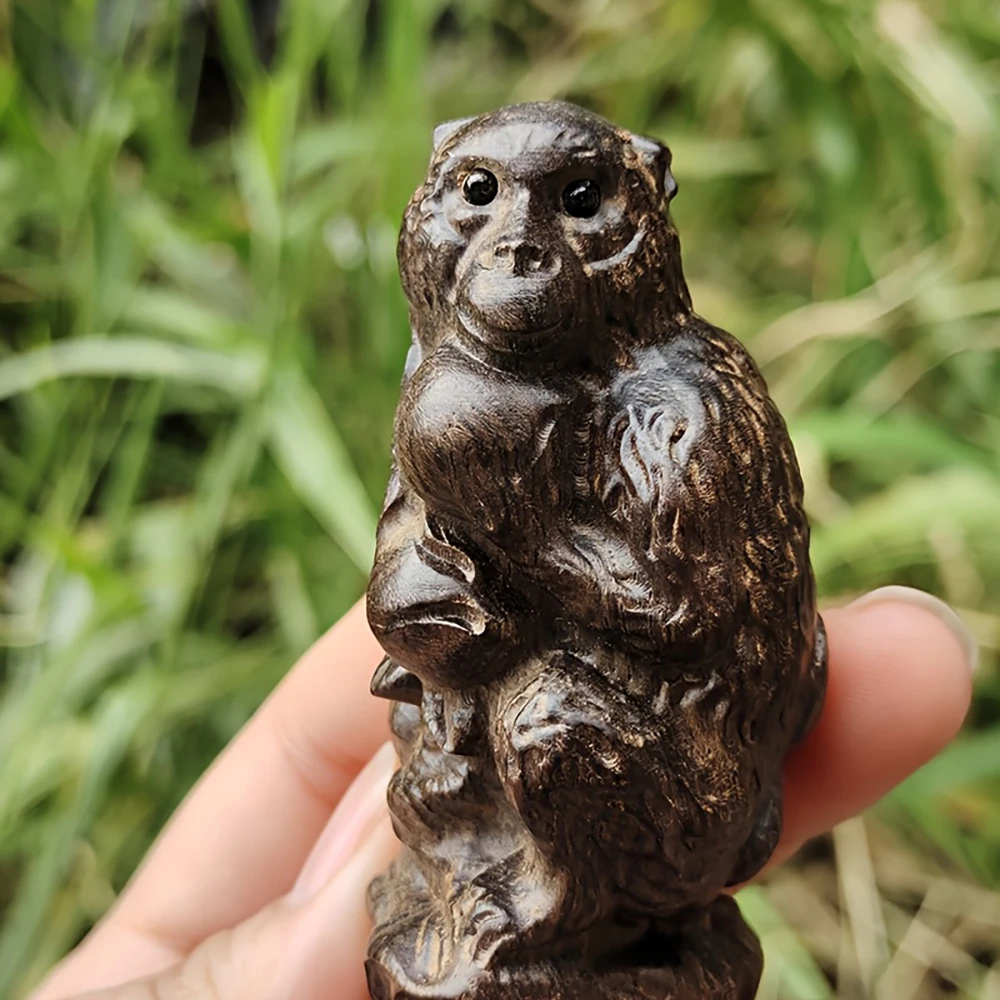 Solid wood carved monkey holding a peach sitting on a tree stump. Creative wooden sculpture of a monkey holding a peach sitting on a tree stump, a decorative statue for home interior tabletop decoration