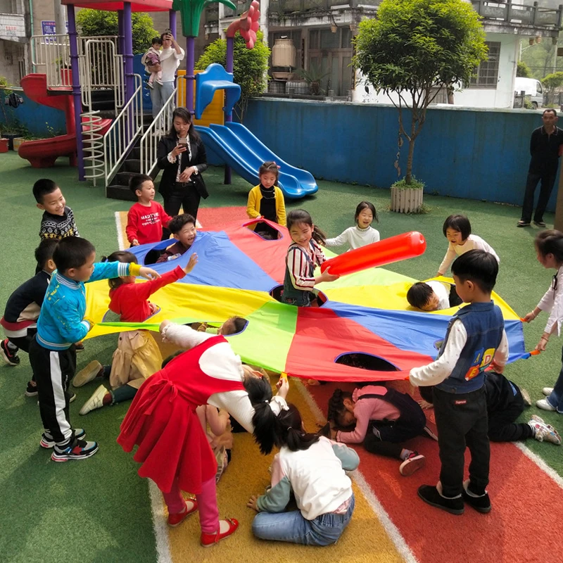 I bambini all'aperto giocano con la tenda del giocattolo dell'arcobaleno del paracadute giochi per bambini parco giochi per l'asilo divertimento delle attività di Team Building della cooperazione