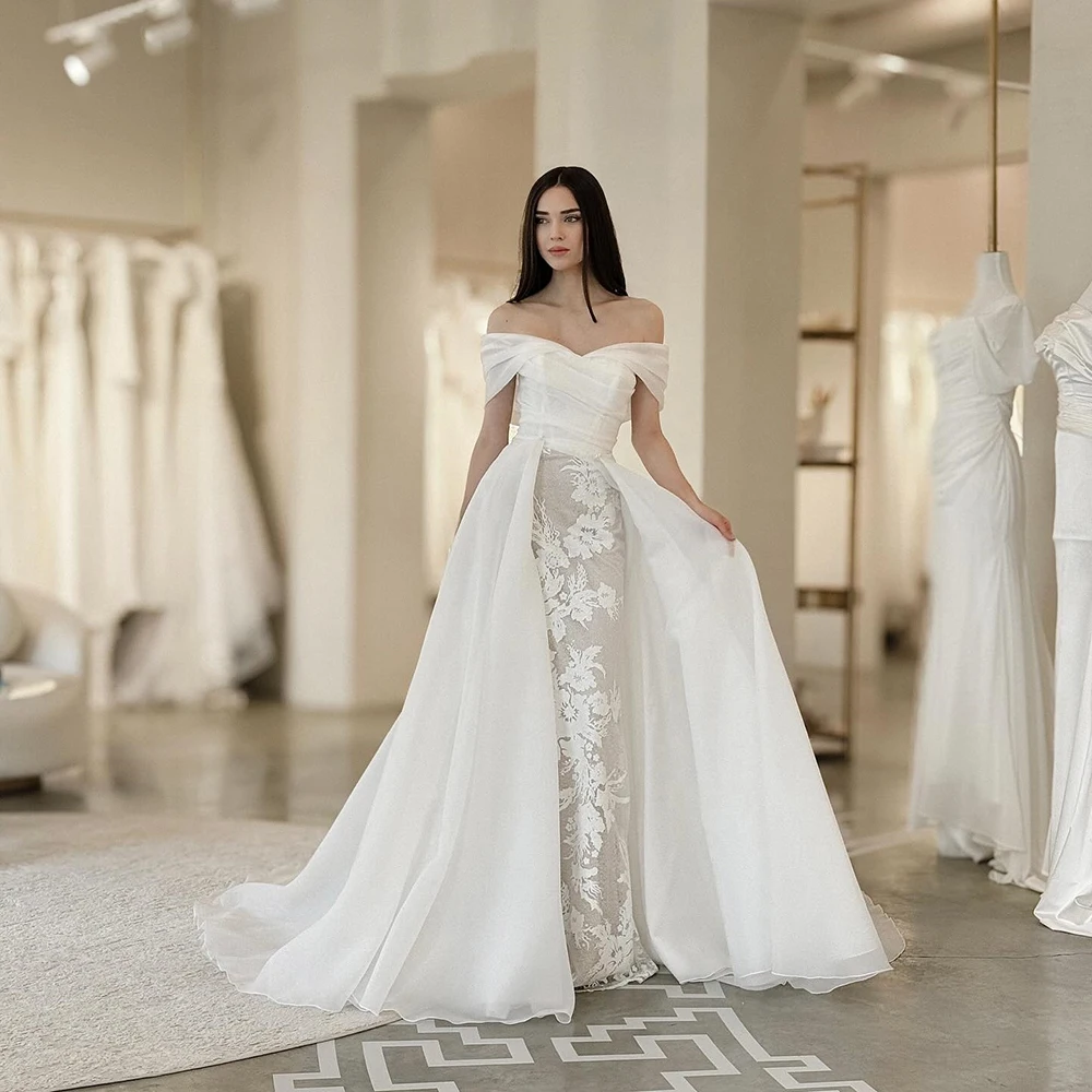 Suknia ślubna z organzy w kolorze białym, z odkrytymi ramionami, aplikacjami, trenem Watteau, odkryte plecy, fason A-line, długość do podłogi.