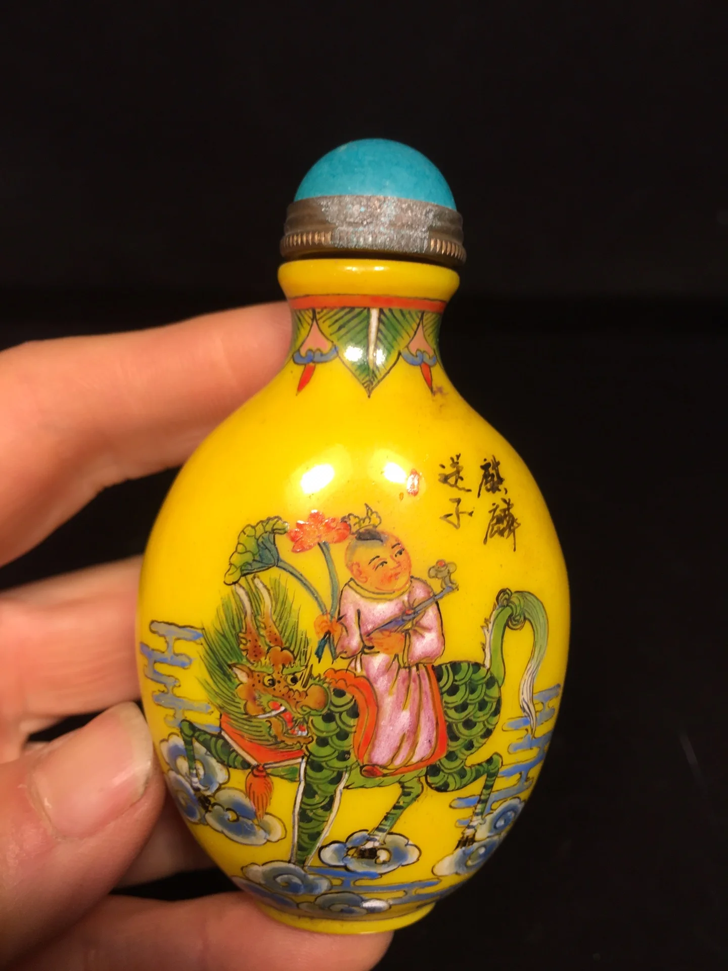 

Made during the Qianlong period, this antique hand-painted glass snuff bottle features a mythical qilin carrying a child on its