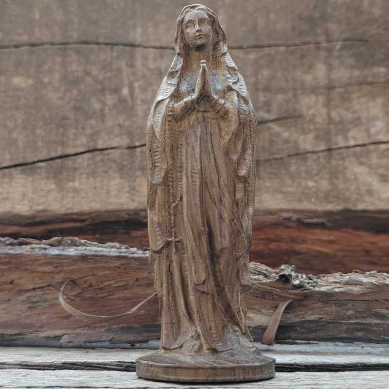 Sculpture en bois à texture de grain naturel de la Vierge Marie en position de prière avec les mains jointes, image sculptée d'une figure priante, robe drapée avec des lignes ondulées, totem spirituel sculpté