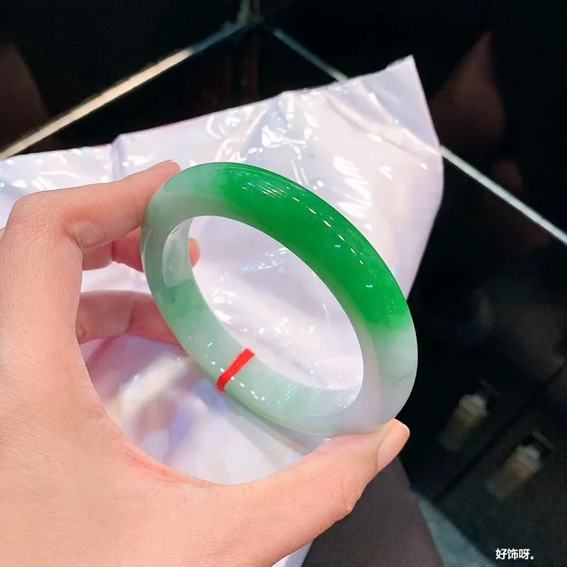 Natural Burmese old mine ice-type jadeite bracelet with green inclusions, featuring a floral pattern, a wide band design, and a