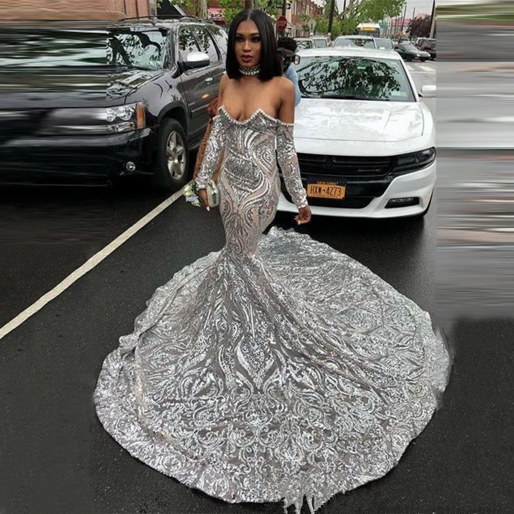graceful-silver-dress-with-off-shoulder-design-and-long-train-features-intricate-patterns-and-sequins-shining-brightly-on-street