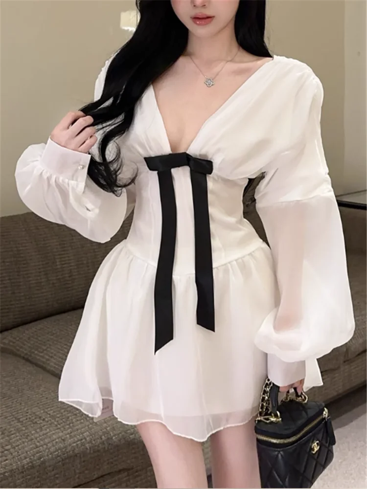 เดรสสั้นสีขาวแบบเซ็กซี่สไตล์ฝรั่งเศส คอวีลึก แต่งโบว์ แขนยาวทรงโคมไฟ ผ้าบาง โชว์เอวเข้ารูป ทรงเอไลน์ เหมาะสำหรับงานวันเกิด