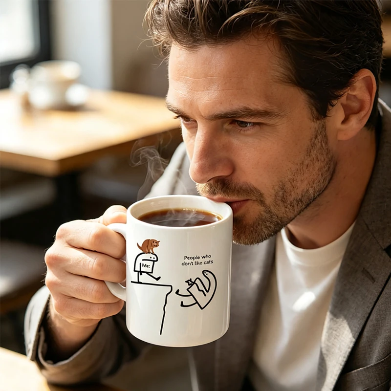 This ceramic coffee mug features a playful cat design and the words 