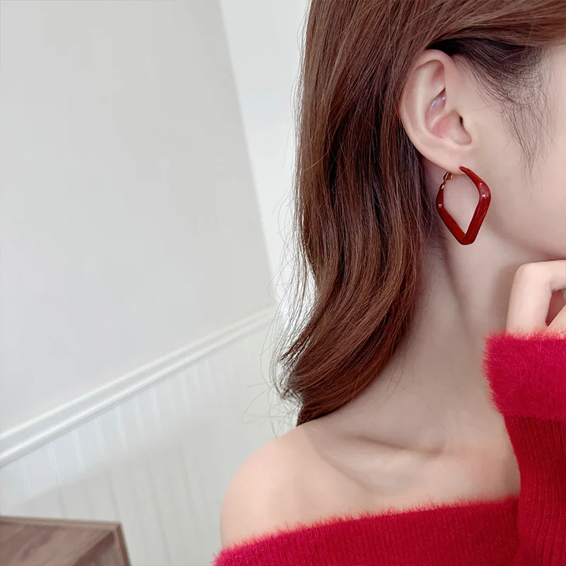 

A simple, retro, niche geometric, fashionable and elegant woman with red ear rings in autumn and winter