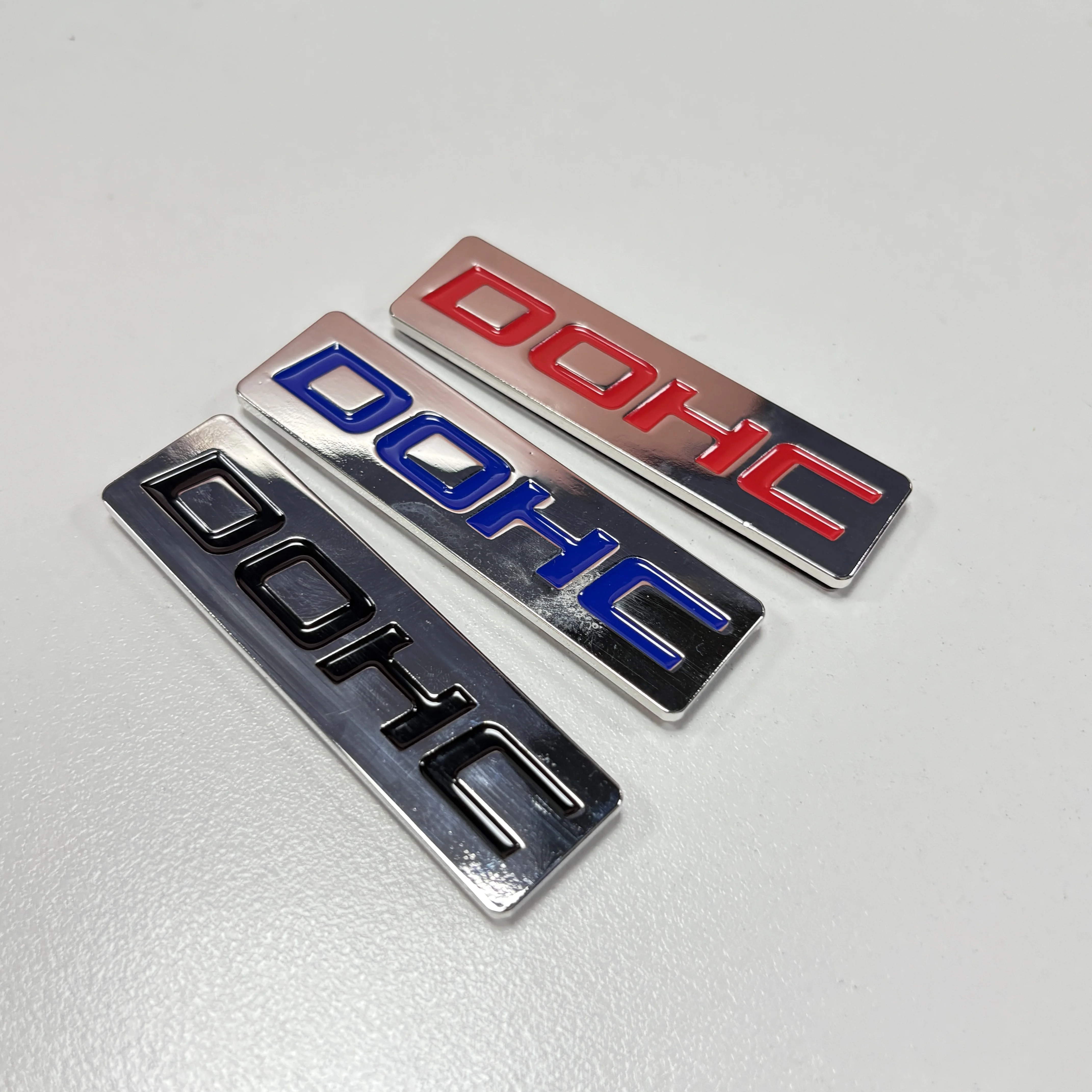 EMBLEMAT METALOWY DOHC MOTYR KORZYSTNYCH ZAWODÓW, NIEBIESKI / CZERWONY / CZARNY, NA BAGAŻNIK, MASKĘ, DRZWI, CHROMOWANY