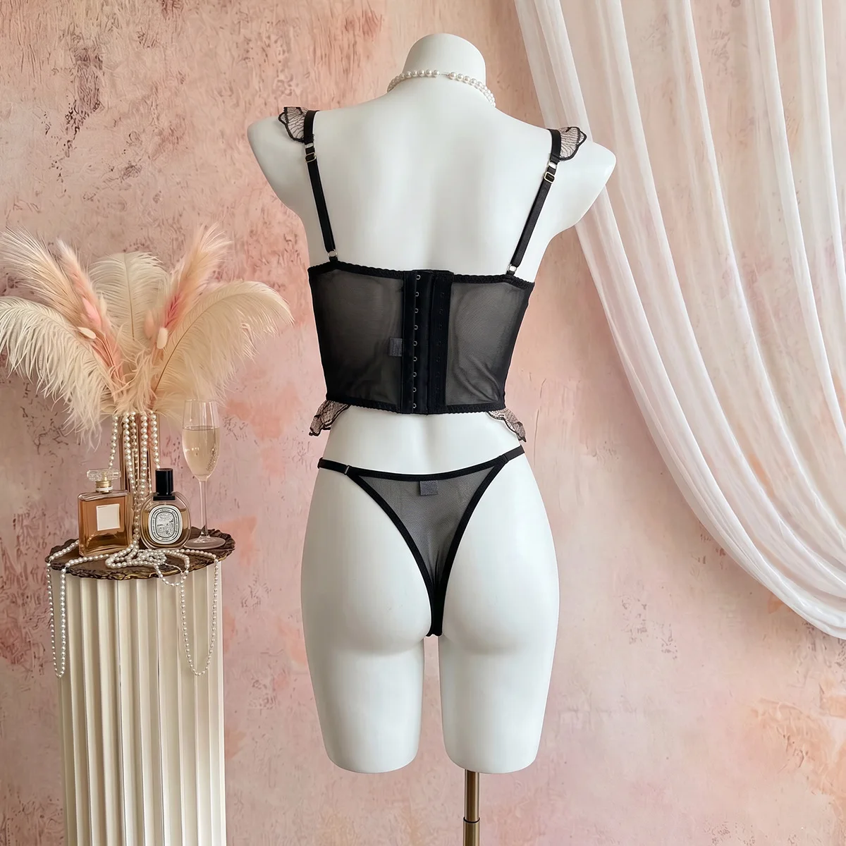 Body corsé negro elegante y romántico, con encaje floral transparente, detalles de volantes, espalda ajustable con cordones y cintura ceñida, lencería moldeadora.