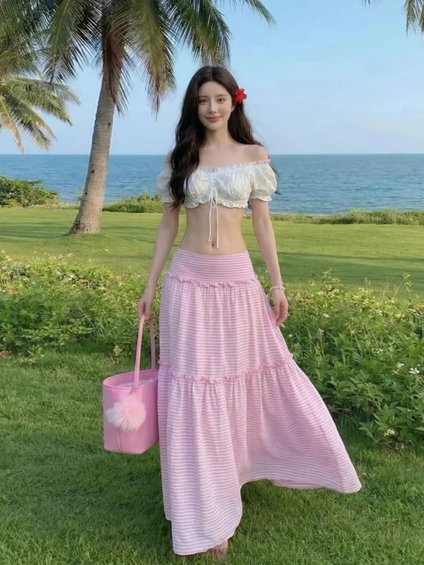 

Комплект женской модной одежды в пляжном стиле: розовый топ на одно плечо с открытым животом и юбка миди с высокой талией в полоску, весна-лето