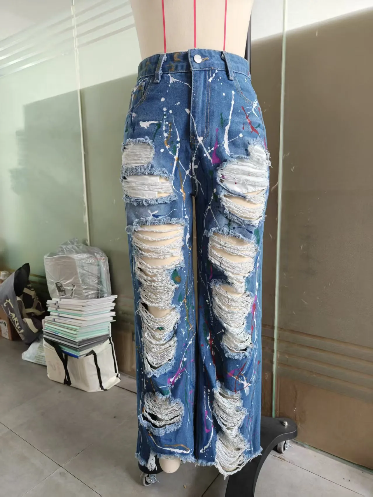 Celana jeans lurus robek dengan motif grafiti yang individual dan modis.