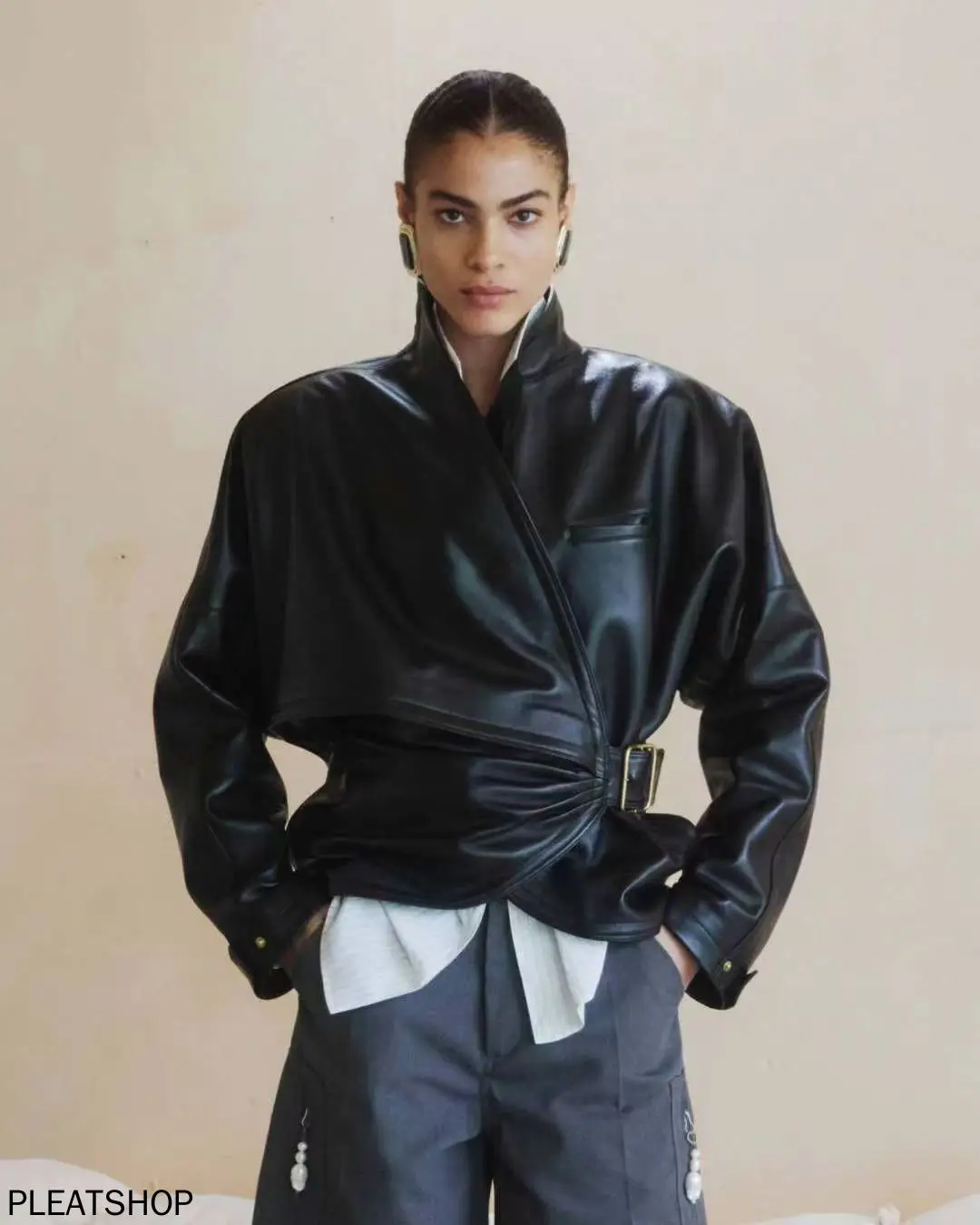 Awangardowa i swobodna kurtka damska na jesień/zimę z ekologicznej skóry proteinowej, modelująca talię, zapinana na klamrę, w stylu owijanym, z stójką.