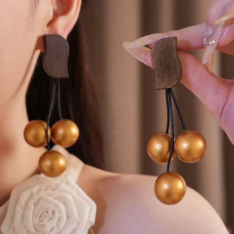 Pendientes largos y brillantes con borlas, de color dorado, con dije metálico y base de madera, para mujer, ideales para fiestas, compras y como accesorio de joyería.