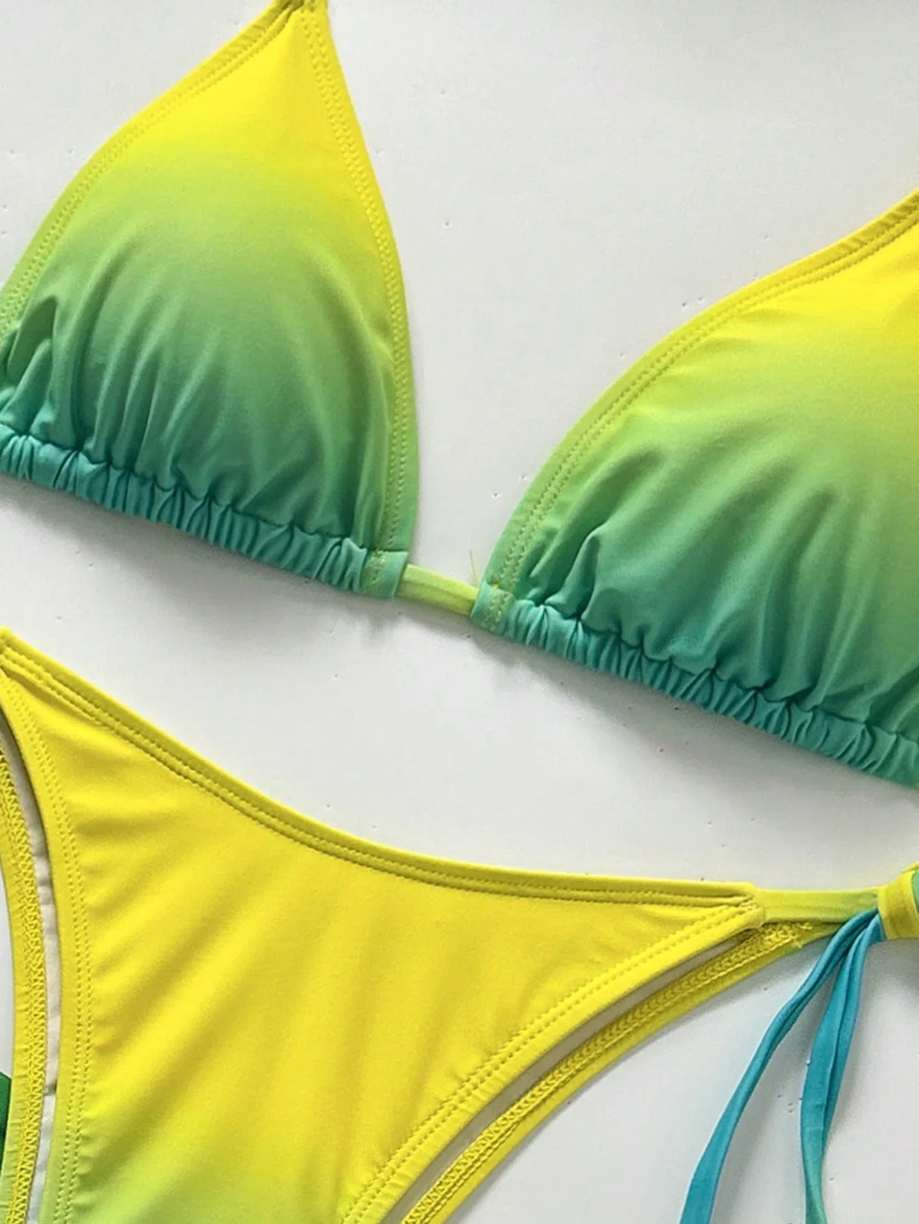 

Яркий комплект бикини с градиентом от желтого к зеленому, с треугольными чашечками, завязками по бокам и облегающим миди-накидкой.