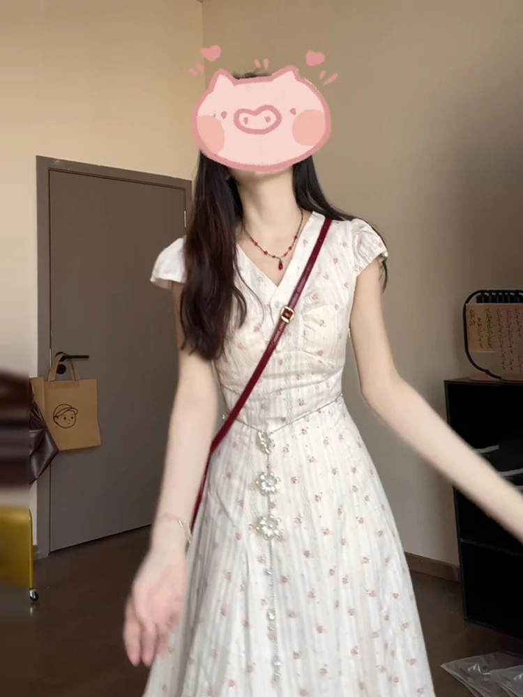 เดรสยาวทรงเอลายดอกไม้สีขาว คอวี สำหรับผู้หญิง ฤดูร้อน 2025 รุ่นใหม่ สไตล์ชายหาด เอวสูง ผ้าฝ้าย หวาน สไตล์เดรสชายหาด