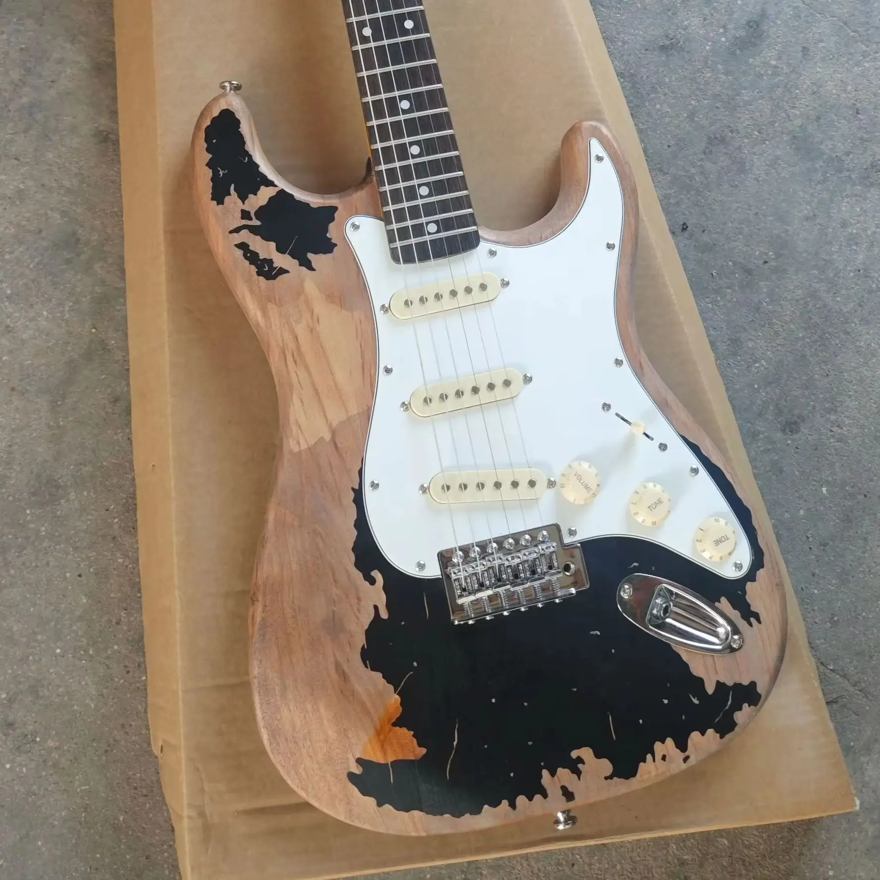 

Black six string electric guitar with distressed treatment, featuring a basswood body, maple neck, and white panel