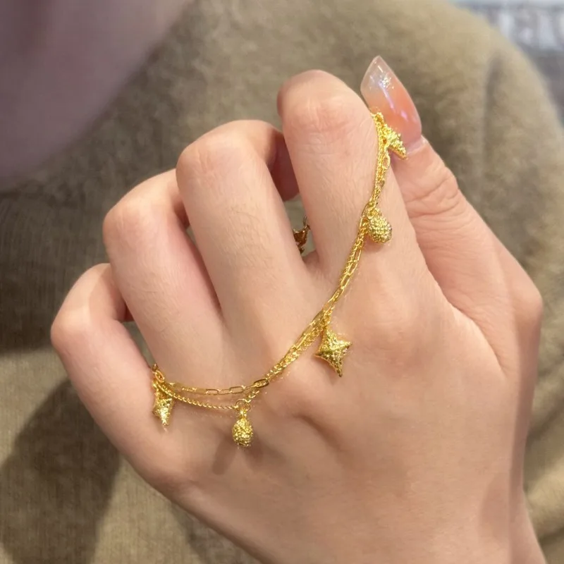 Bransoletka damska w stylu light luxury, złota, z gwiazdą czterokątną, niszowy design, wyrafinowany, podwójny łańcuszek, do noszenia warstwowo, ekskluzywna.