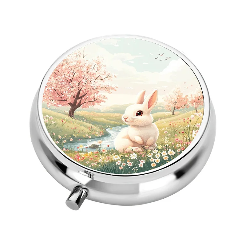 A travel-friendly pill box with a three-compartment design, featuring a spring bunny pattern. This decorative vitamin storage box is perfect for keeping in your bag or purse, made of metal, and is ideal for organizing pills while on the go or as a gift.