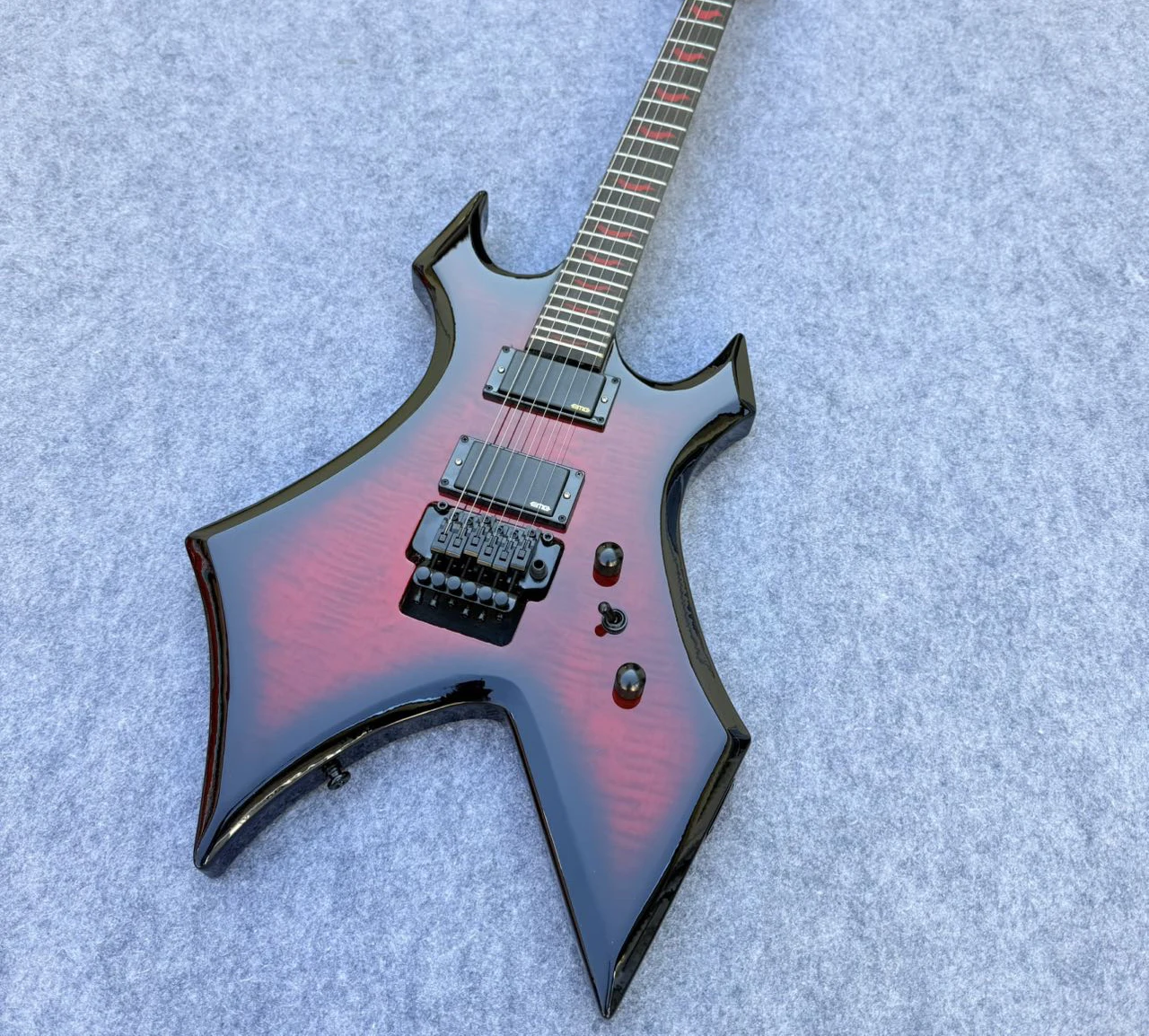 

Высококачественная гитара "Warlock", с гибким мостиком Floyd Rose, фиксированным струноутягивающим механизмом, активными звукоснимателями, верхней декой из пламенного клёна, в наличии. Модель 2026.