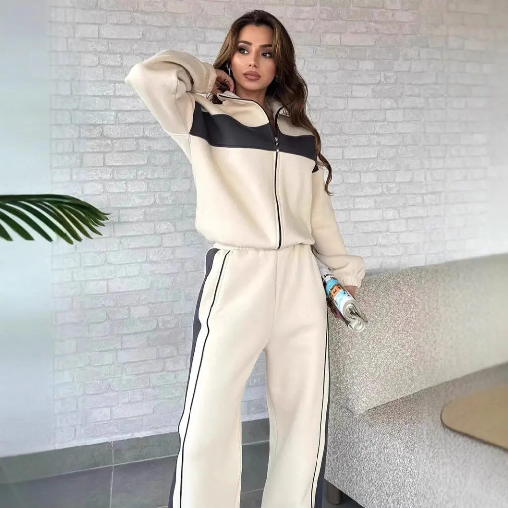 Damski zestaw w stylu casual streetwear: bluzka z wysokim kołnierzem i zamkiem błyskawicznym oraz proste spodnie w kontrastowe paski, dwuczęściowy komplet.