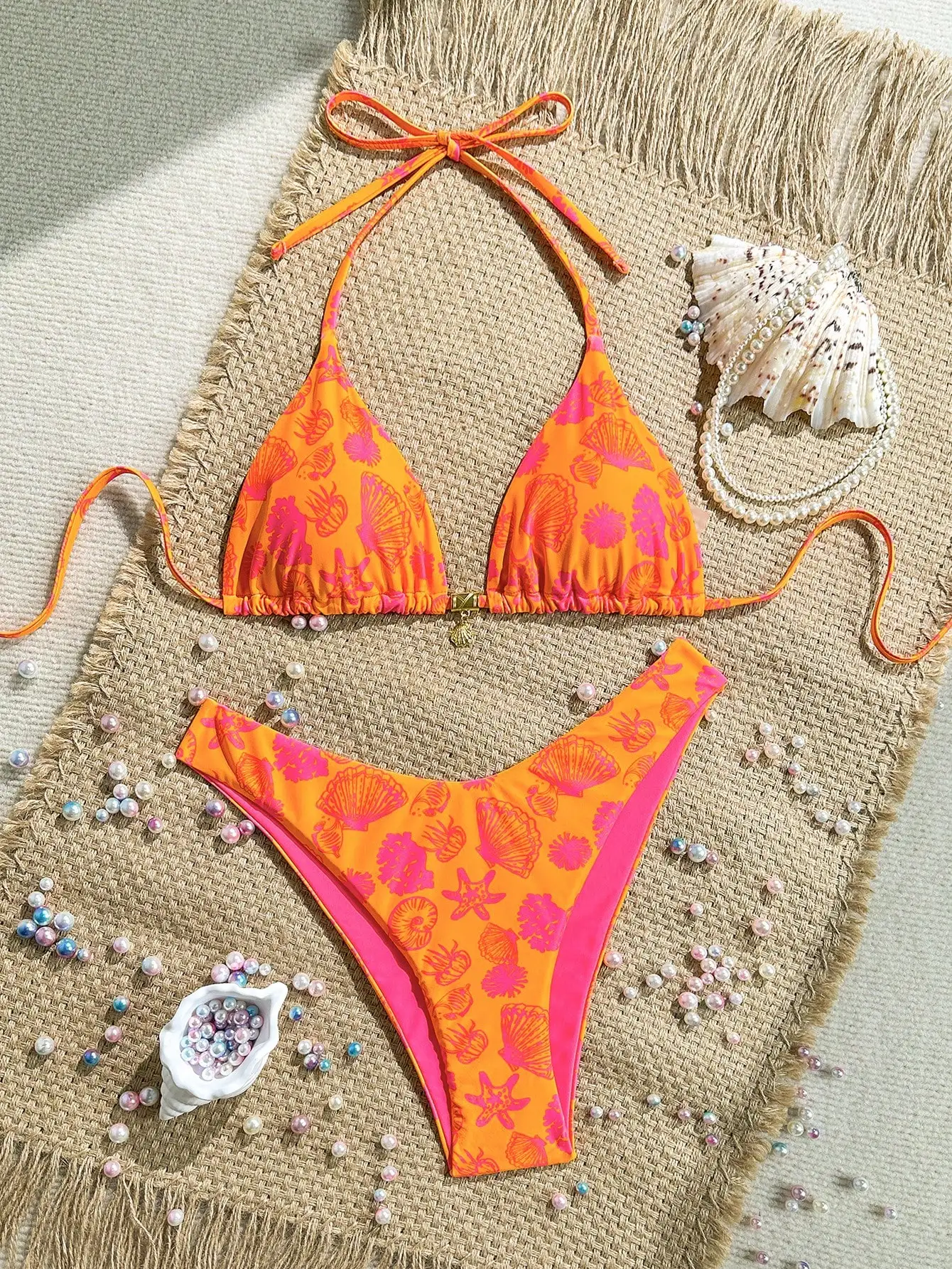 

Яркий комплект бикини с принтом в виде ракушек оранжевого и розового цветов, с завязками на шее и высокой талией.