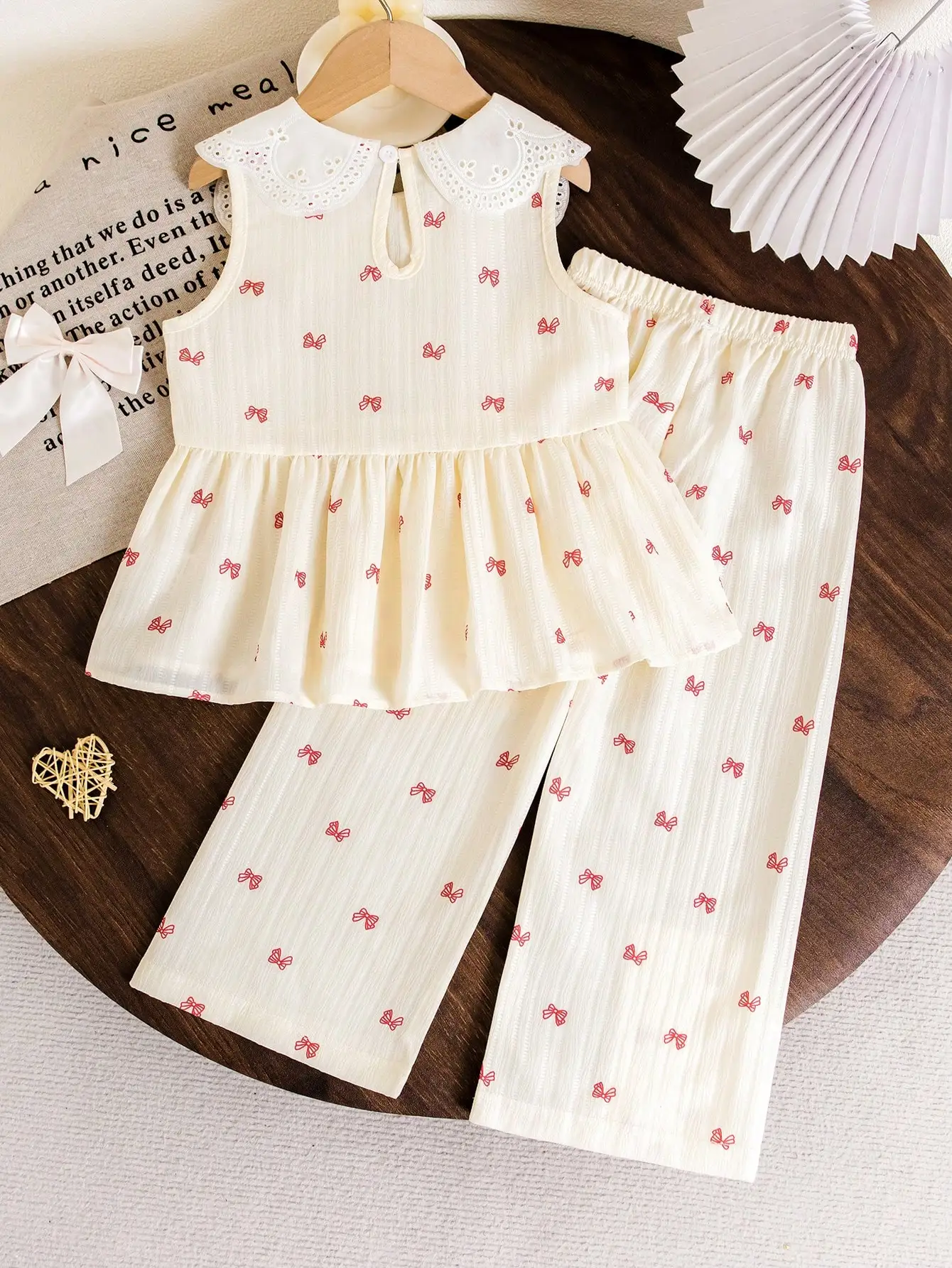 Little Girl's Off-White Bowknot Large Lapel Suit, with Red Bowknot Print on an Off-White Base, Featuring an Exquisite and Cute Large Lapel Design, Sleeveless Top + Long Pants Style, Suitable for Spring and Autumn School Trips, Family Gatherings, and Vacation Photoshoots, Showcasing the Gentle and Sweet Temperament of Little Girls. Spring and Summer.