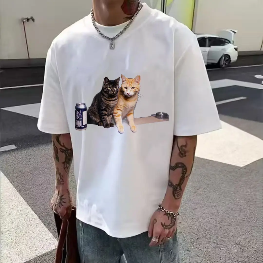 تي شيرت أبيض بتصميم مطبوع لقطط تابي باللون الرمادي الداكن والبرتقالي الفاتح جنبًا إلى جنب، علبة مشروبات داكنة على اليسار، موزع شريط #6