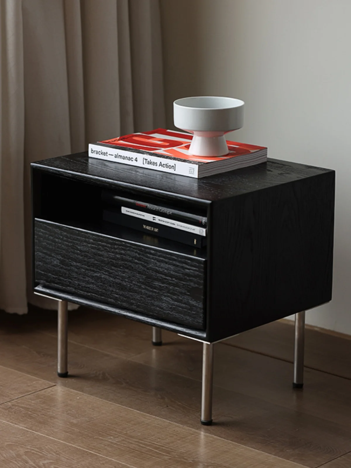 The bedroom bedside table is minimalist, modern and creative, with stainless steel legs and a black color scheme. The bedside image 2