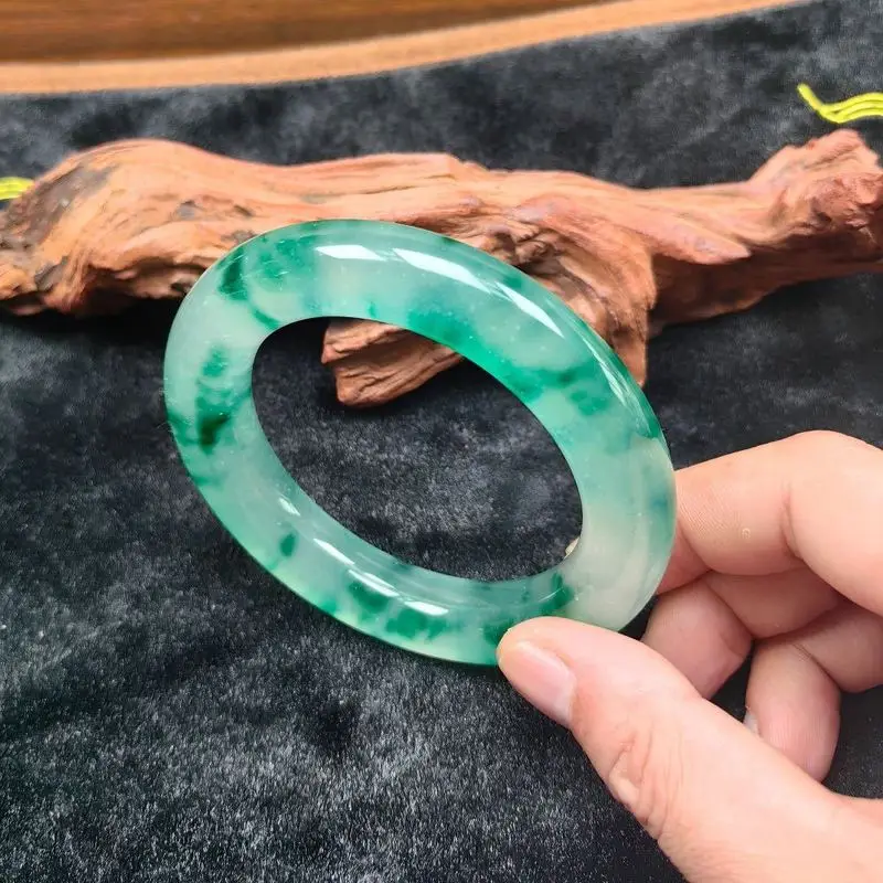 A white background with a vibrant green, round bracelet that exudes a translucent, luminous, and emerald-like quality, adorned w
