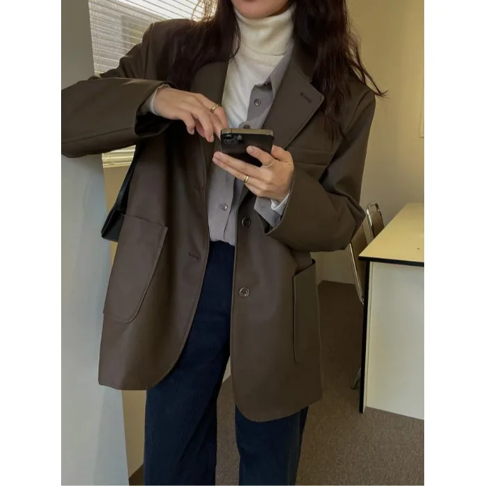 Długi płaszcz ze skóry PU z luźnym krojem i kołnierzem garniturowym, modna odzież wierzchnia dla młodych kobiet na sezon jesienny.