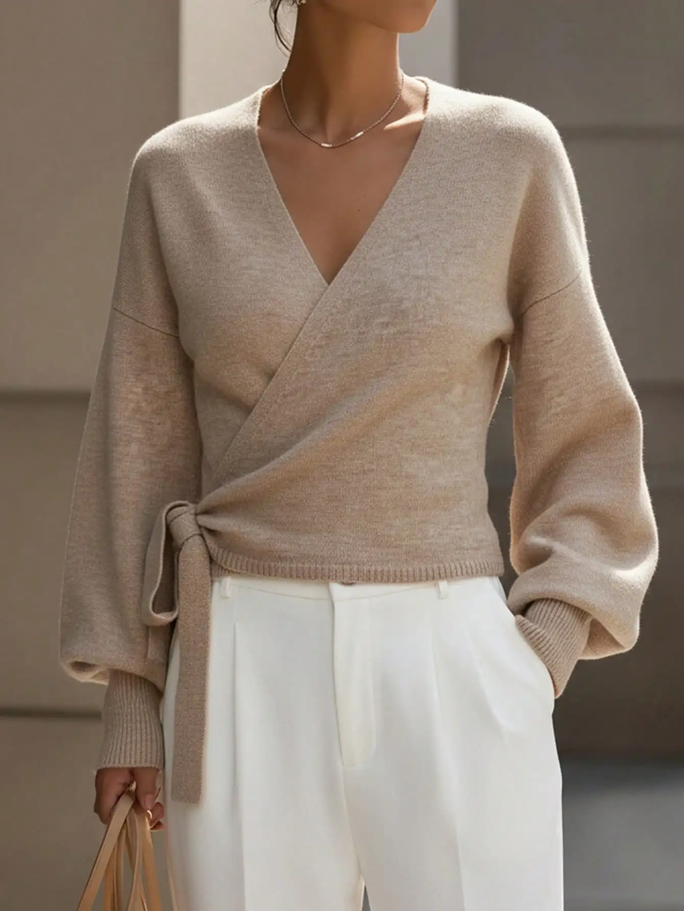 

Бежевый укороченный вязаный свитер с V-образным вырезом, завязками на талии и рукавами-гигот.