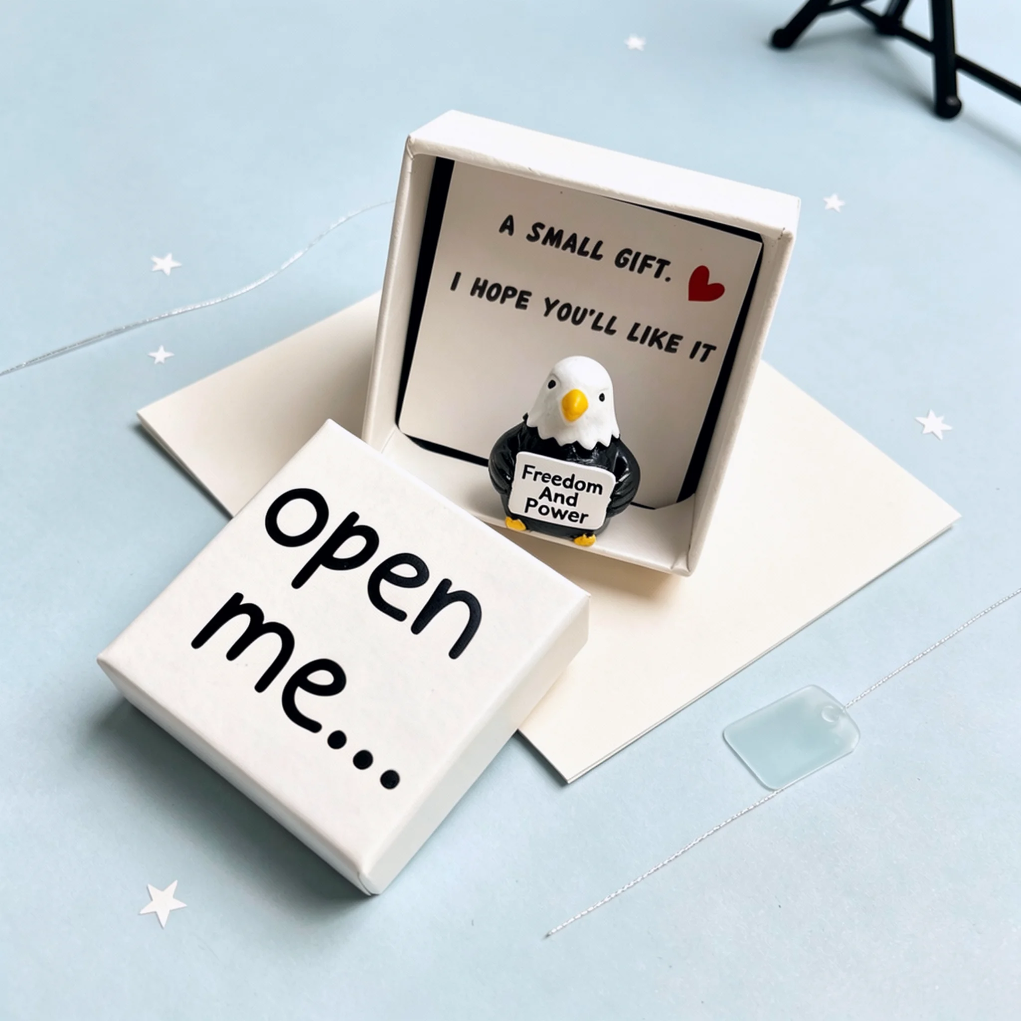 Le charmant coffret cadeau surprise 'Ouvre-moi' comprend un aigle en résine symbolisant la liberté et le pouvoir, un petit cadeau et une carte inspirante.