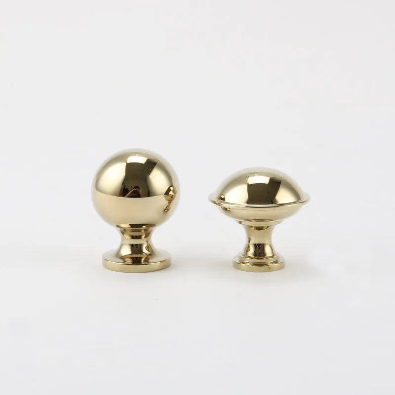 Two rounded gold brass cabinet knobs standing upright