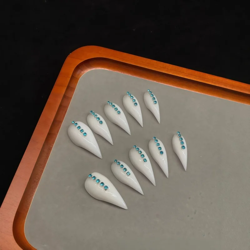 10pcs pure white dagger-shaped fake nails, paired with blue crystal sequin chain-shaped pointed fake nails.