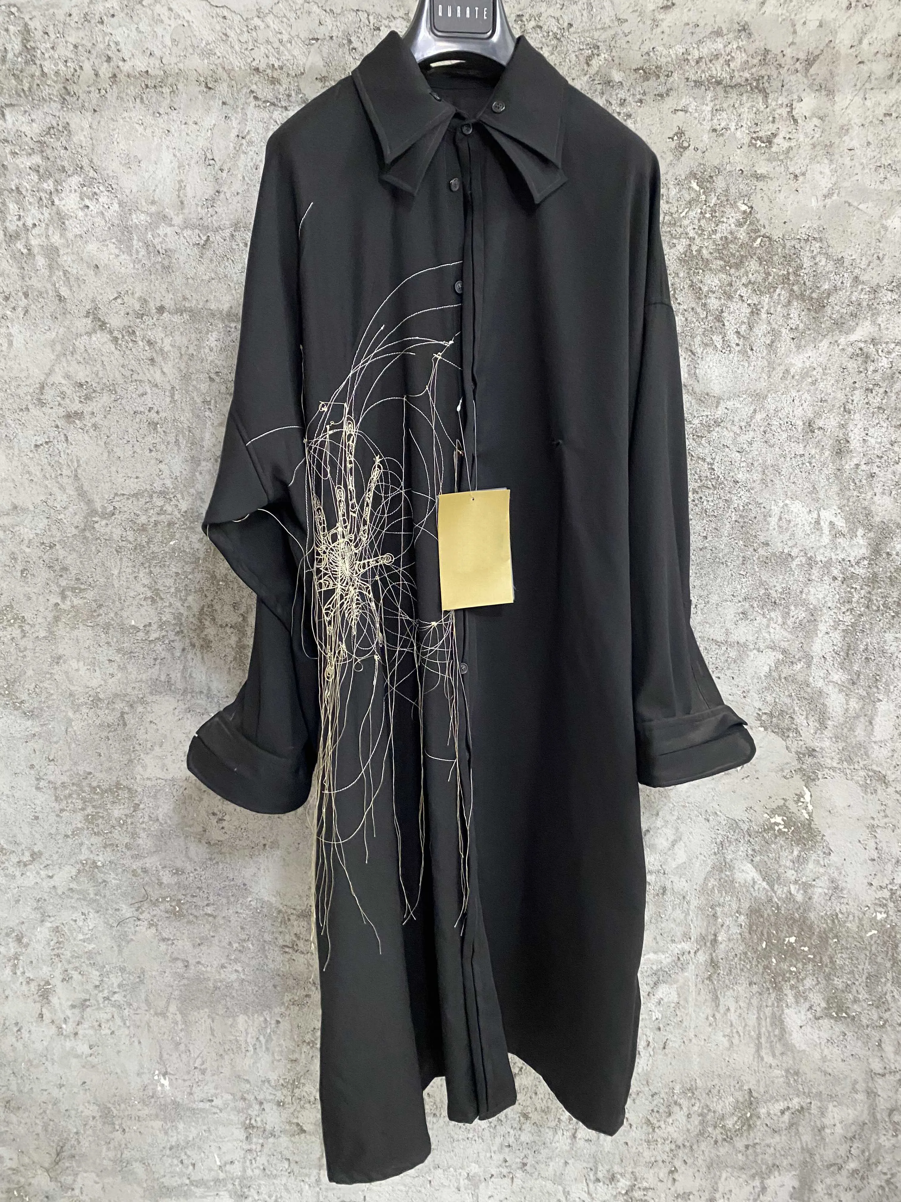 A designer of a long Tokyo robe with wool spider embroidery and flowing thread