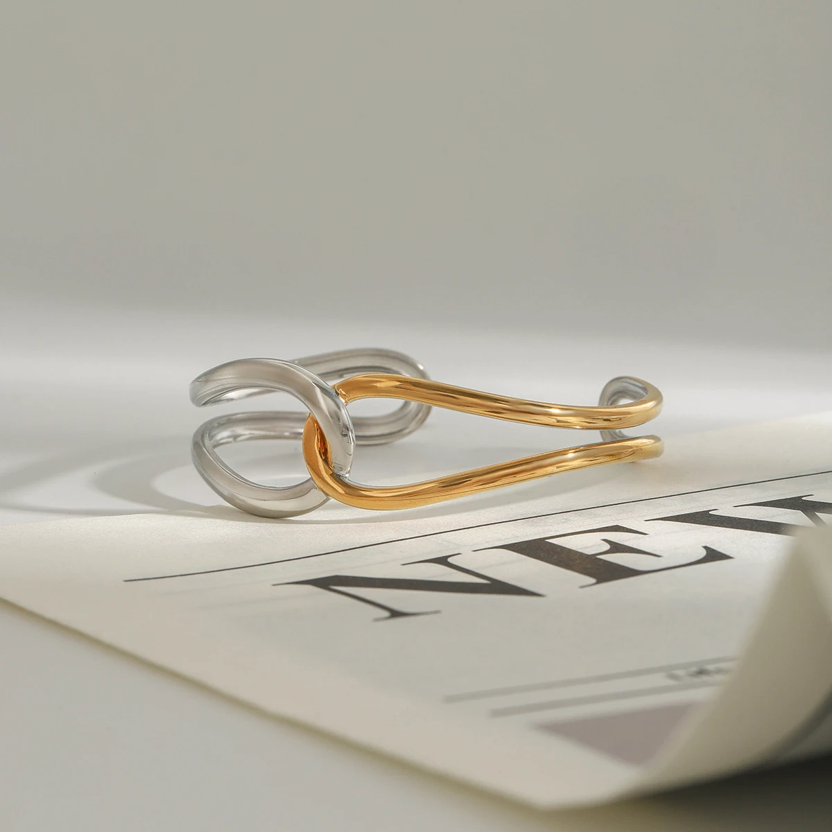 سوار AIKOER بسيط مطلي بالذهب عيار 18 قيراط من الفولاذ المقاوم للصدأ بلونين مع خطوط ملتوية وعقدة سوار مجوف للنساء J