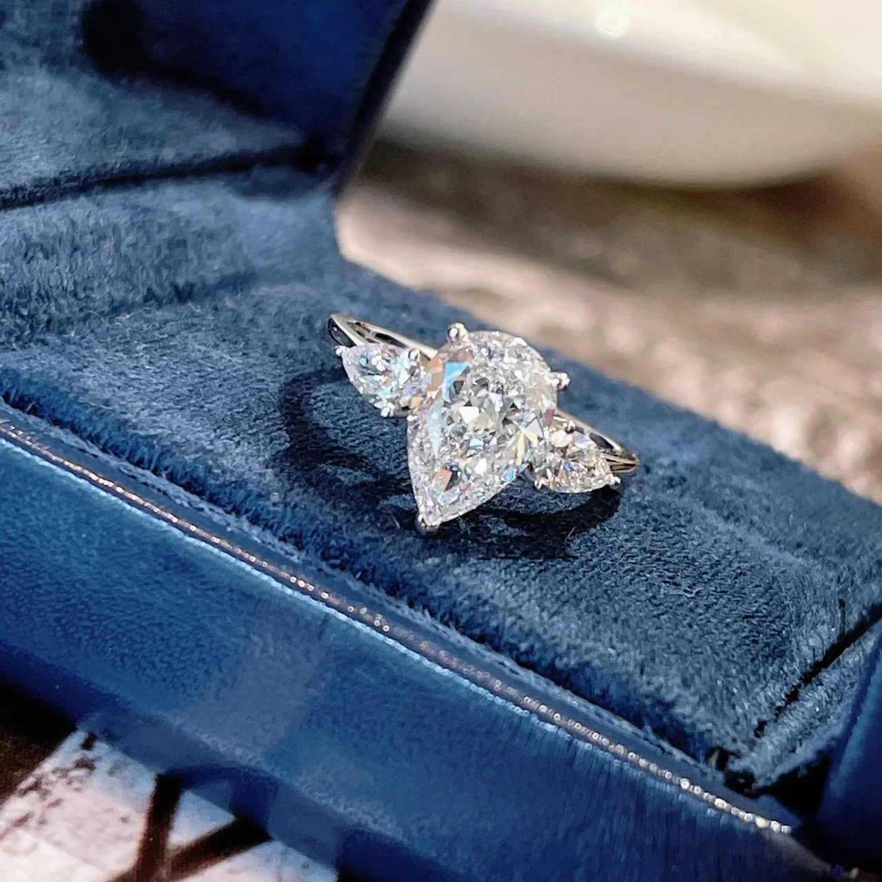 Drop-shaped adjustable ring crafted from copper with white gold plating featuring three simulated moissanite stones set in geome