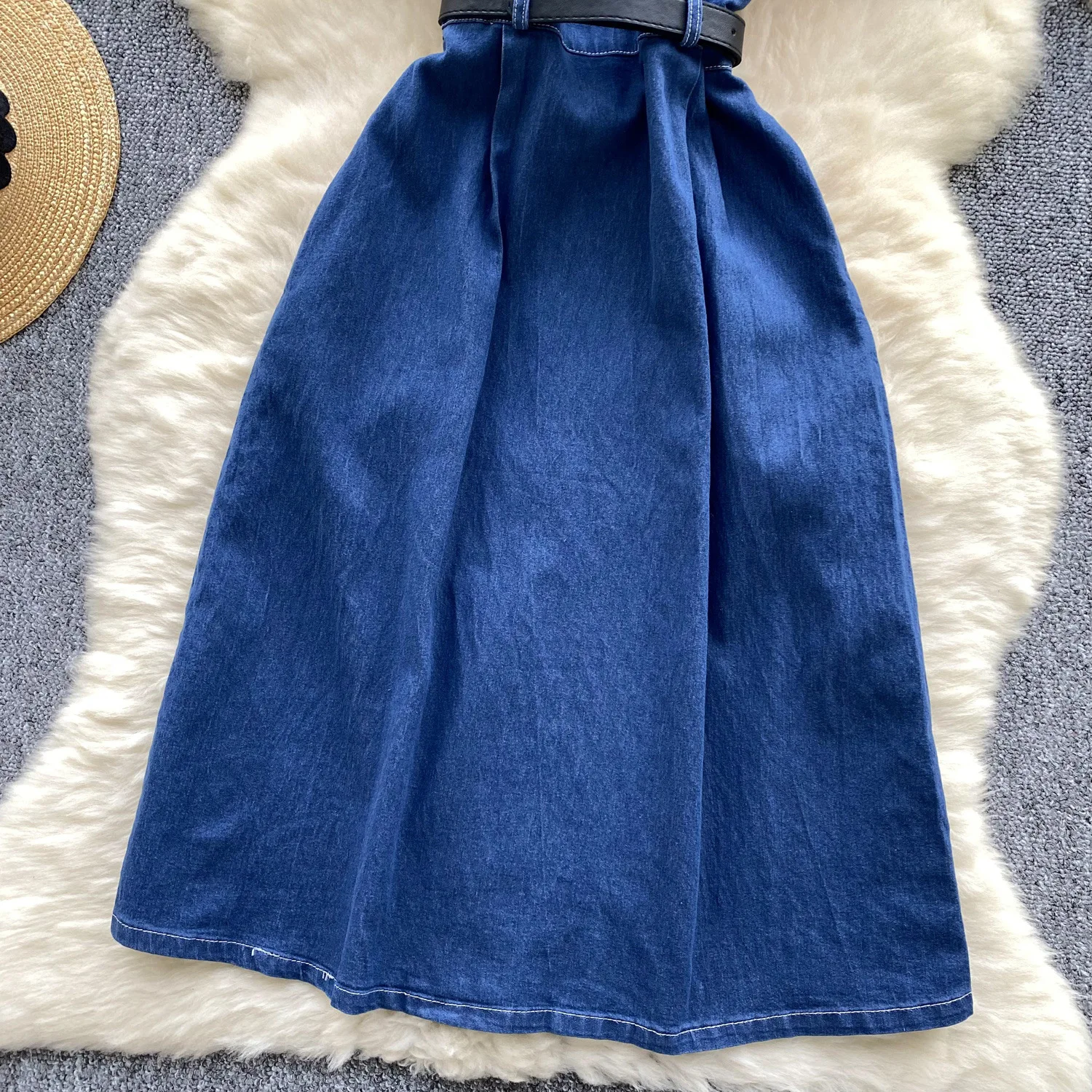 Un nuovo abito in denim alla moda estiva. Abito in denim a vita stretta con cintura monopetto in metallo a maniche corte con collo alto retrò per le donne