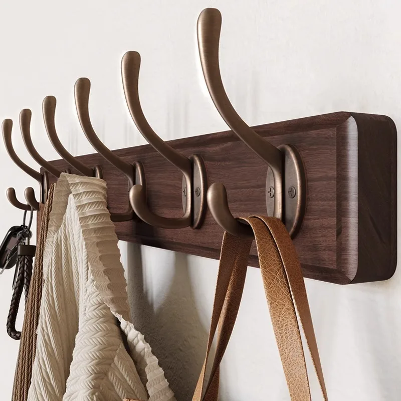 Clothes rack on the wall, hooked clothes on the wall, entrance door, entrance door, and bedroom behind the entryway