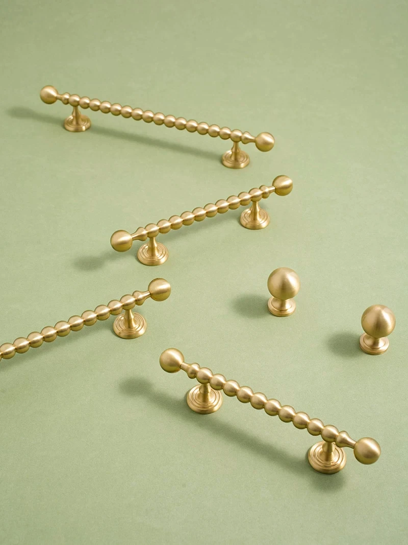 Brushed brass handle and knob range arranged on green