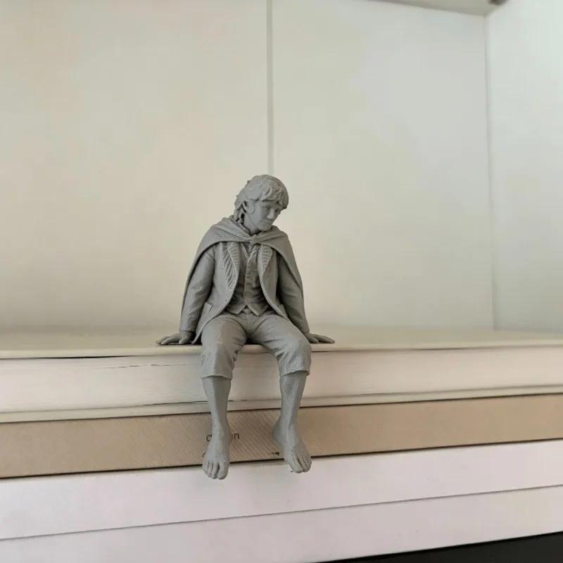 1/3 Piece Set of a Humble Traveler Figurine for Display on the Edge of a Shelf or Desk, Featuring a Classic Cape and Barefoot Design, with Legs Hanging from the Shelf, Making It the Perfect Companion Statue for a Home