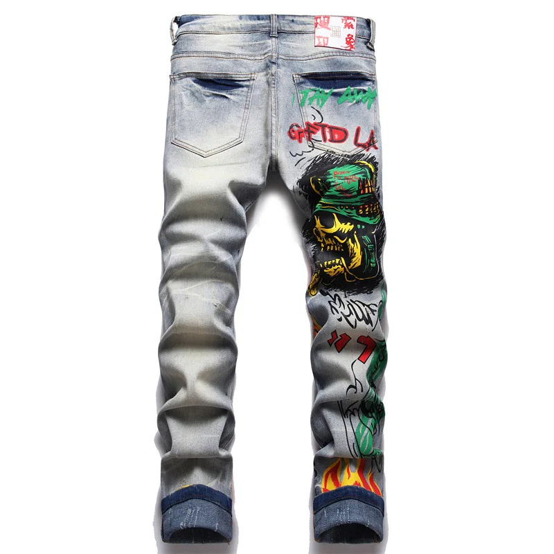 Jeans in Denim elasticizzato da uomo con stampa Streetwear personaggio teschio dipinto a fiamma pantaloni Vintage bottoni pantaloni sottili strappati