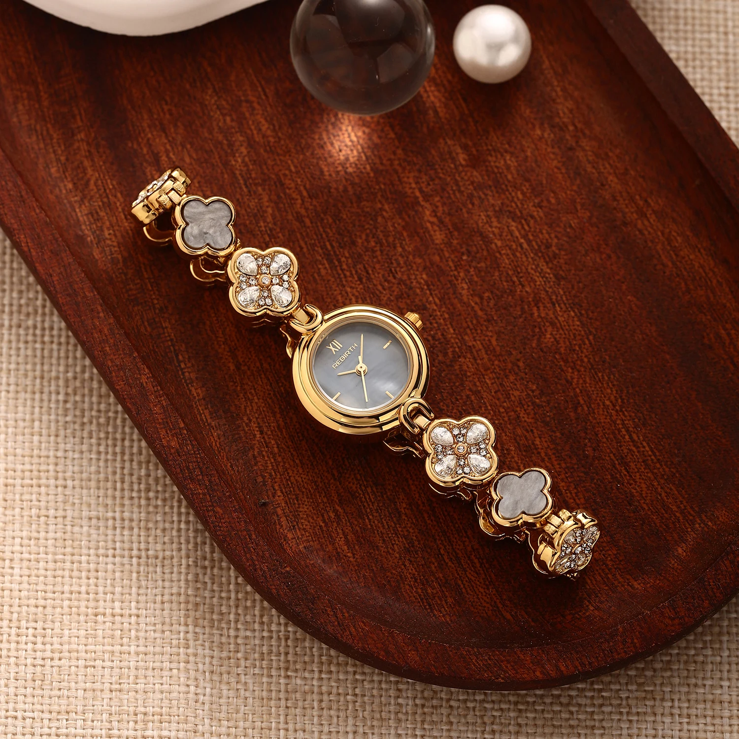 Luxurious four-leaf clover diamond-encrusted women's quartz watch with natural mother-of-pearl small round dial and Roman numerals, mother-of-pearl and rhinestone inlaid with gold-plated steel bracelet, elegant women's wristwatch