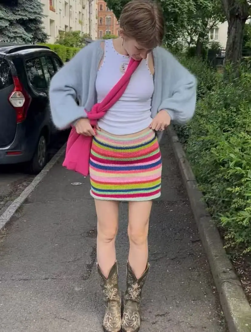Colorful striped knitted short skirt highlights height, reduces age, small person closes eyes, wraps buttocks