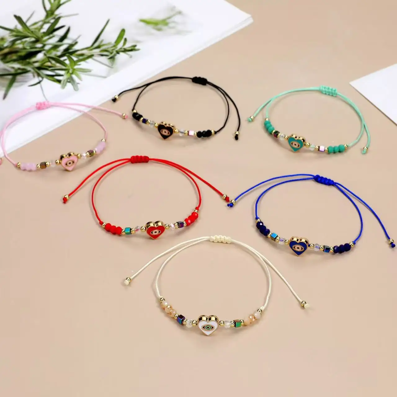Un juego de 12 piezas de pulsera ajustable de moda europea y americana tejida con cristales de mal de ojo y corazón que gotea aceite