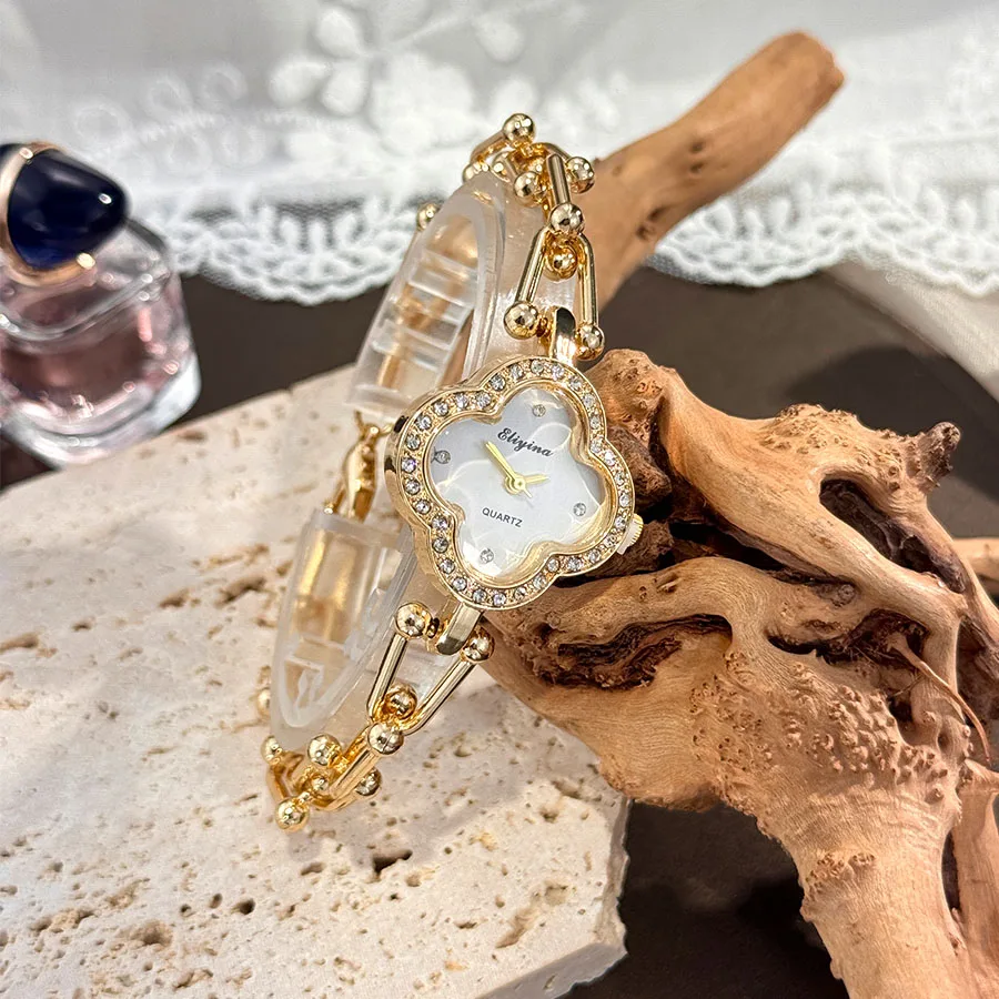 

Женские часы с дизайном в виде четырехлистного клевера, золотой цепочкой и безелем, украшенным камнями.