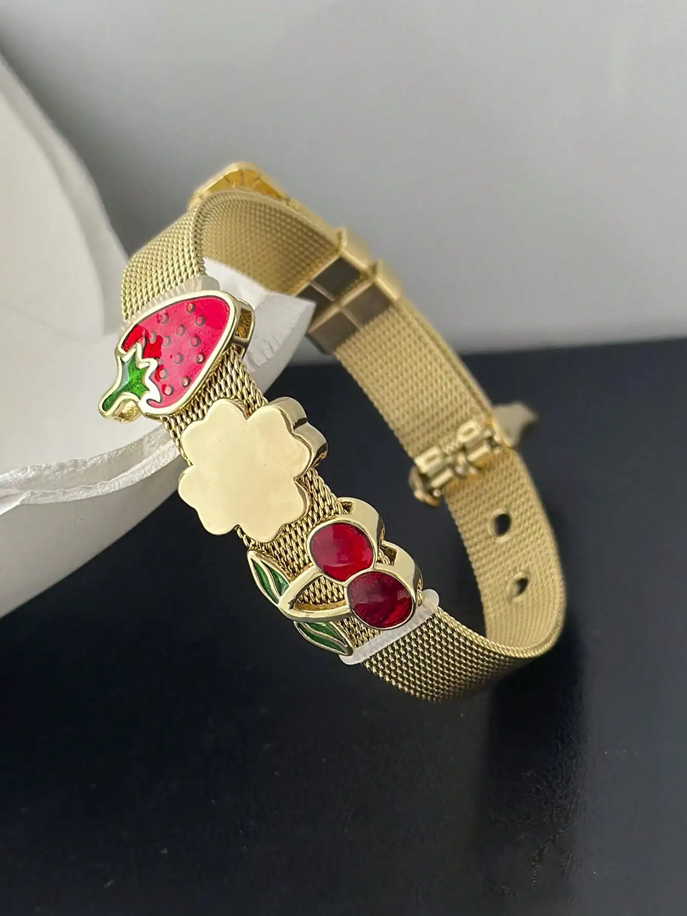 

Золотистый сетчатый ремешок для часов с подвесками в виде фруктов: клубника, вишня и цветы.