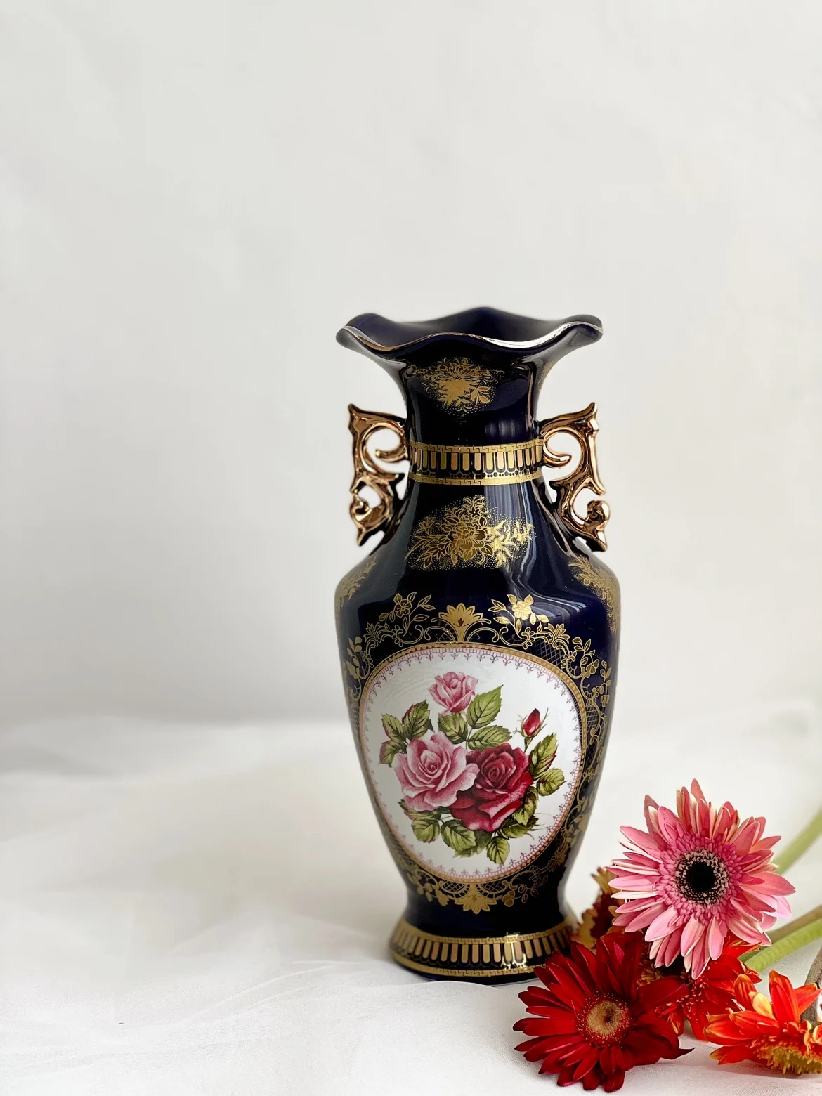 Vintage European style vase with blue glaze, featuring figures, flowers, and ceramic vases