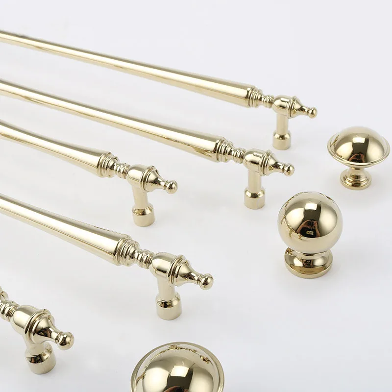 Gold cupboard pulls beside two rounded knobs
