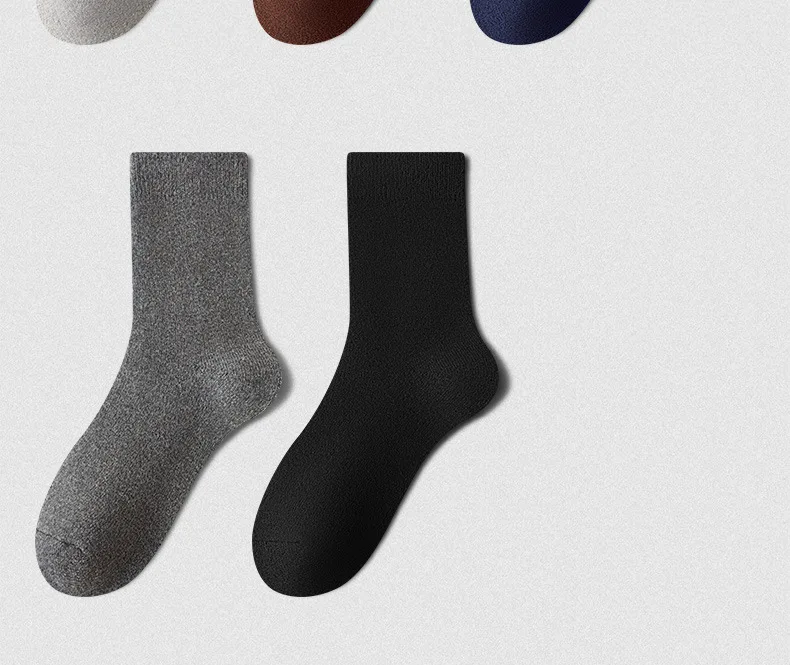 Un par de calcetines de lana de invierno suaves para hombres con diseño liso gris y negro, de largo hasta el tobillo.