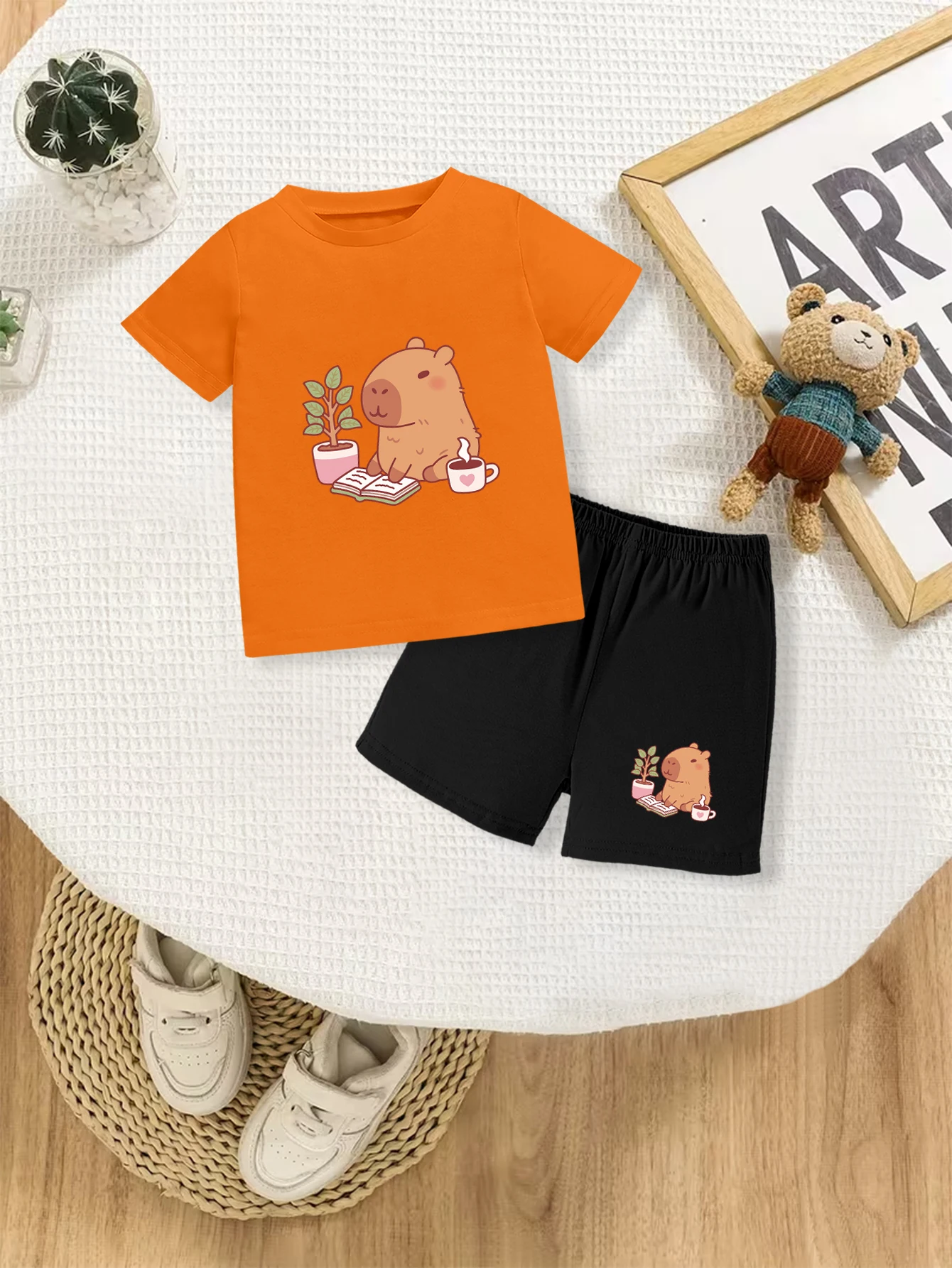 

Комплект из 2 предметов: летняя повседневная футболка и шорты для мальчиков с принтом в виде мультяшной капибары, читающей книгу.